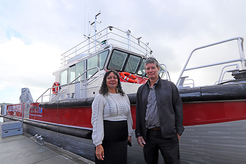 Tui Shortland and Jim Lyle standing in front of the vessel Waikare II.