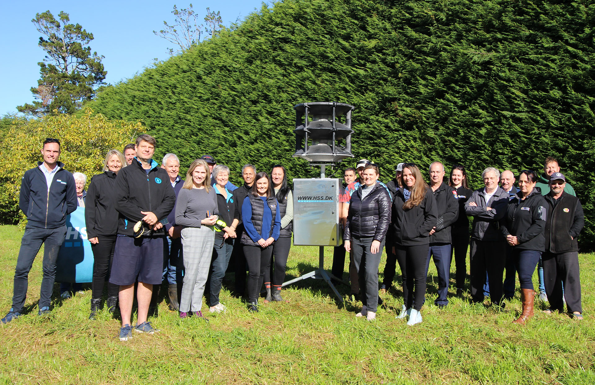 Group of people with tsunami siren in a field.