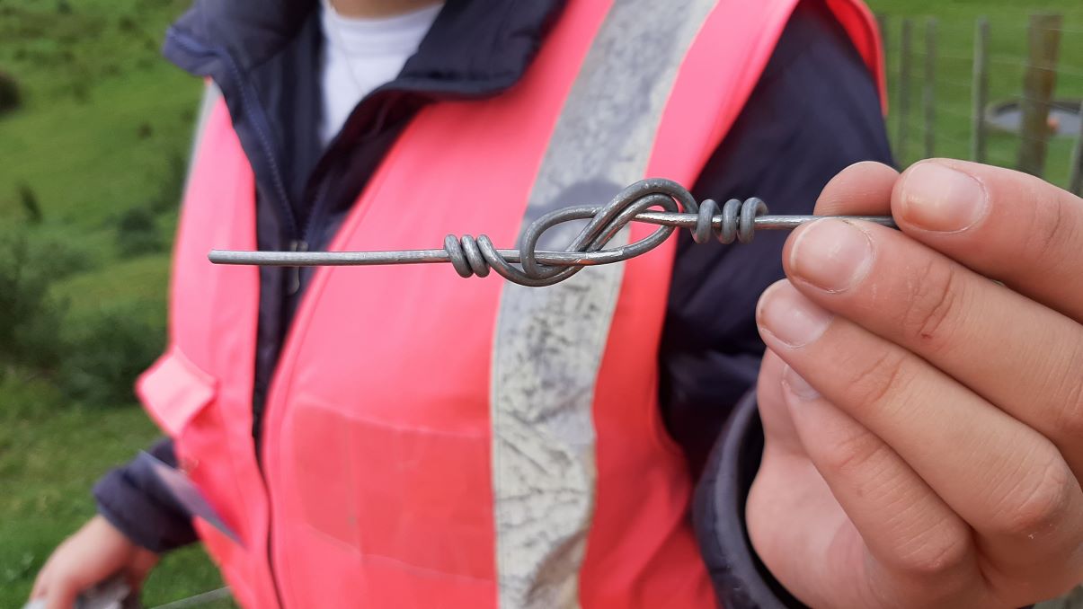 Hand holding knot in wire.