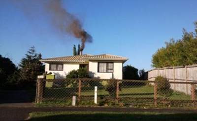 Description: House with black smoke from chimney. 