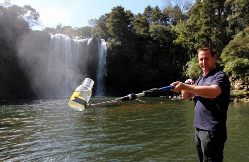 Environmental Monitoring Officer Adam Phillips holds a sampling bottle and pole.