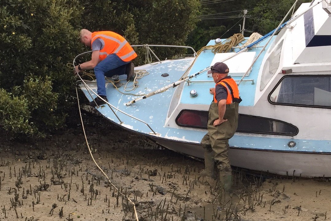 Two men secure grounded boat.