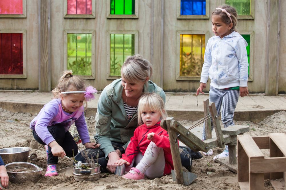 Woman and children in sandpit.