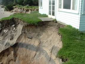 House on the waterfront on the edge of a bank that has eroded after a storm.