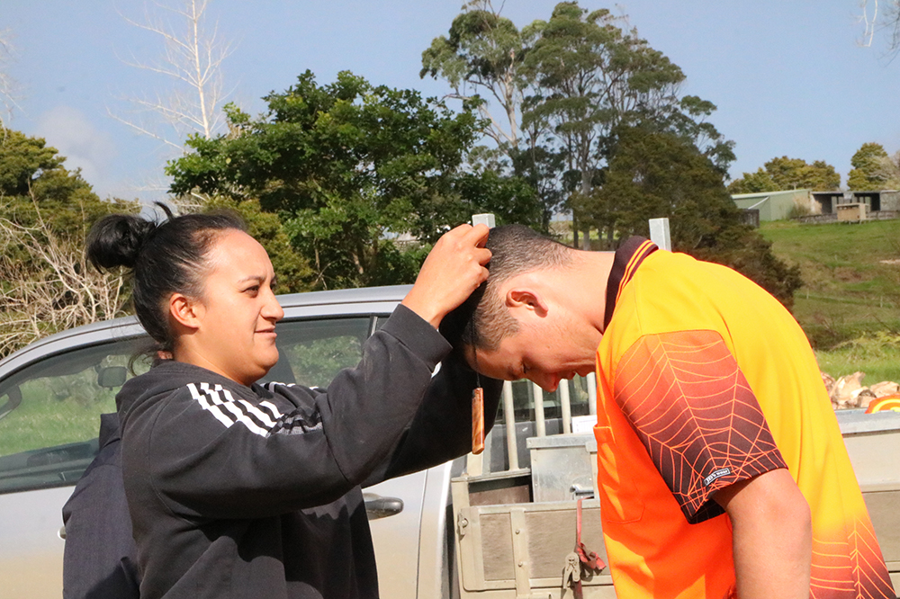 Woman placing kauri pendant over man's head.