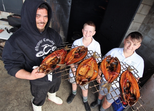 People holding the fresh smoked mullet.