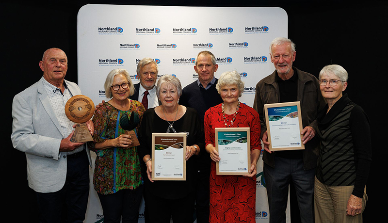 Group of men and women with three certificates and a trophy in front of Northland Regional Council logo backdrop. (Photo: Dawn Dutton Photography).