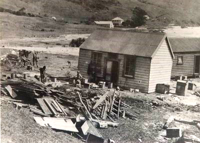 Black and white photo of old buildings and damaged equipment.