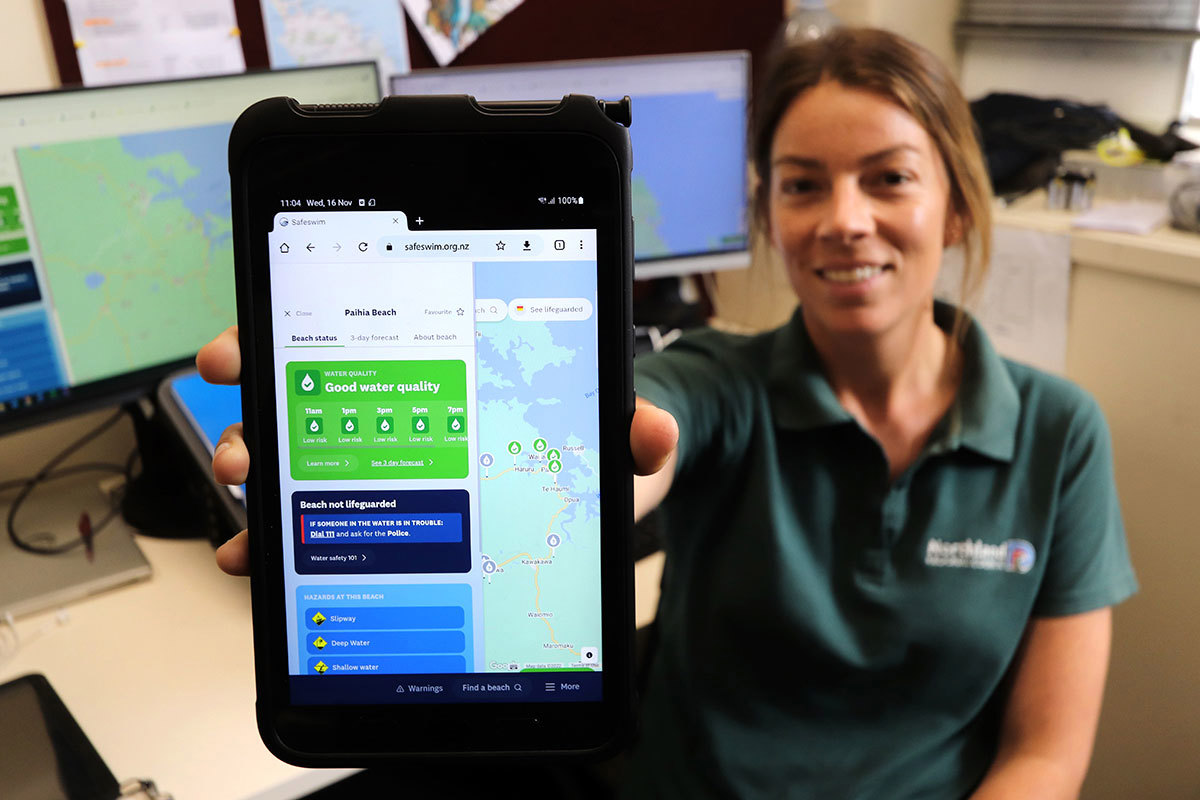 Woman holding phone displaying Safeswim website.