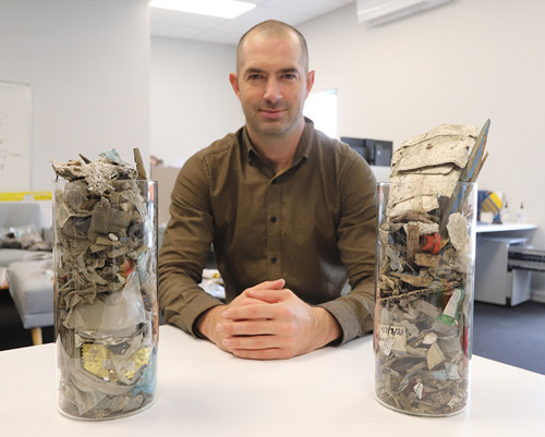 Man sitting with two jars of collected litter.