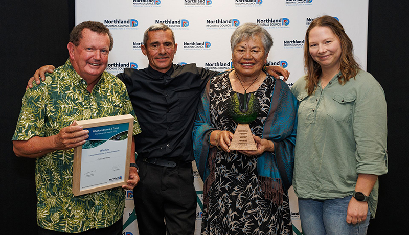 Two men and two women with winner's trophy and certificate in front of Northland Regional Council logo backdrop. (Photo: Dawn Dutton Photography).
