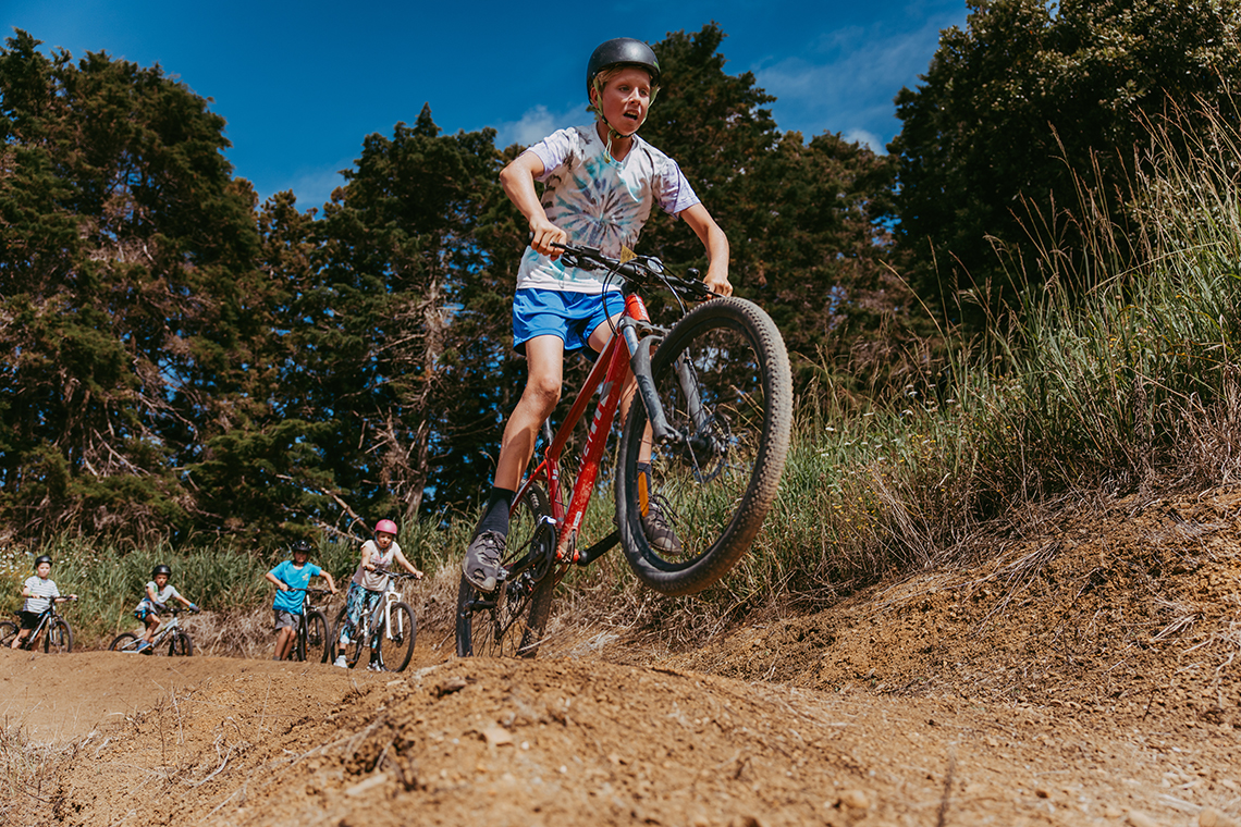 Boy on bike jumping a gap on a dirt track.