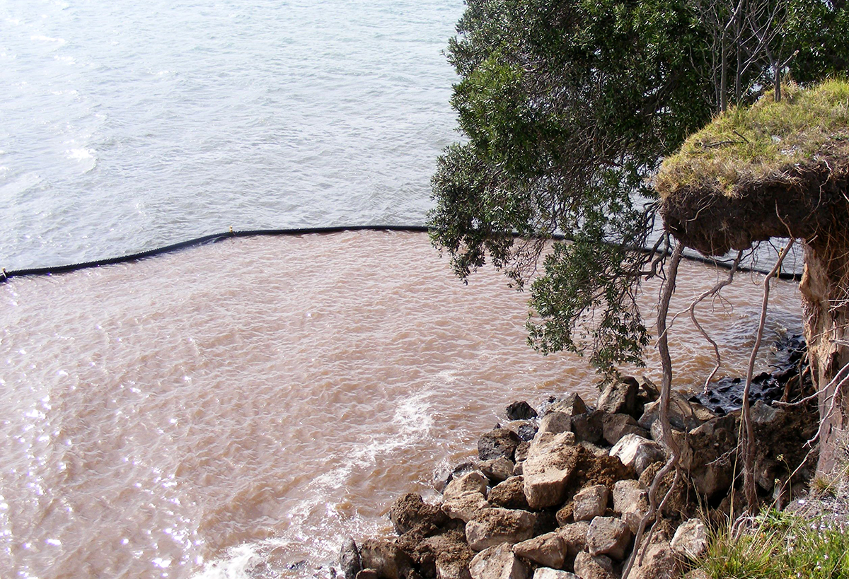 Looking down on a black silt curtain holding back sediment in the sea.