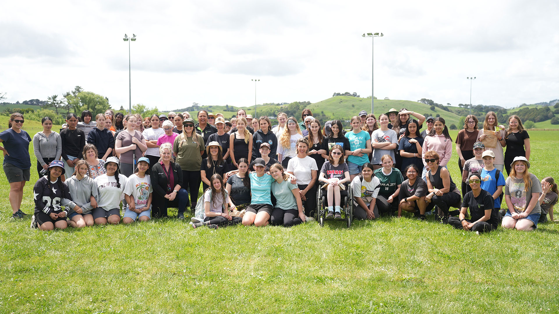Group of 70 women together on a grass field.