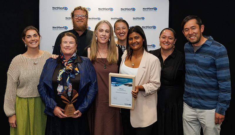A group of men and women with trophy and certificate in front of Northland Regional Council logo backdrop. (Photo: Dawn Dutton Photography).