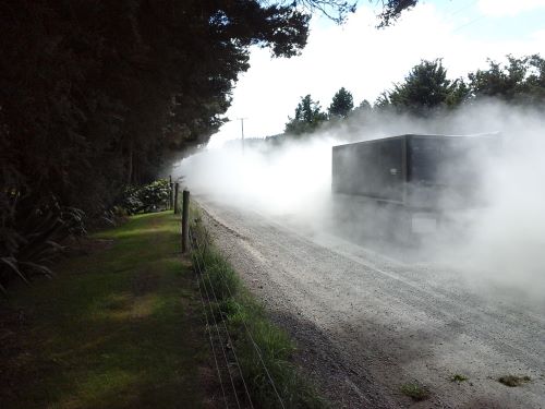 Truck driving on dusty road.