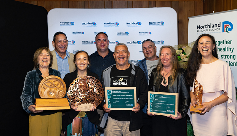 Group of people holding trophies and certificates.