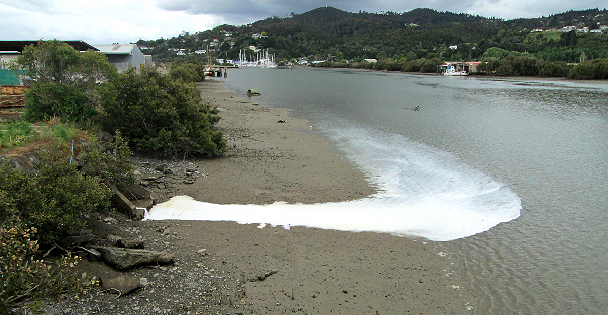 White paint discharging from a pipe into the channel.