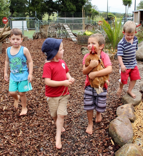 Children in outdoor area with a chicken.