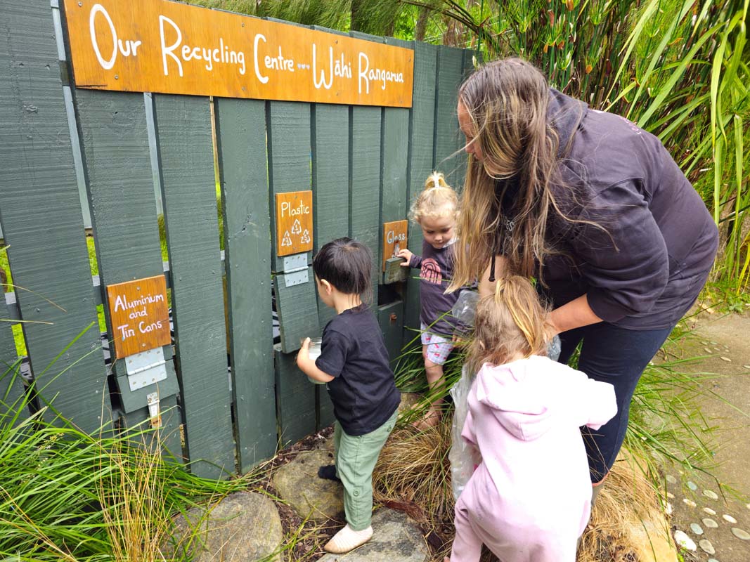 Two children and one adult pointing to fence.