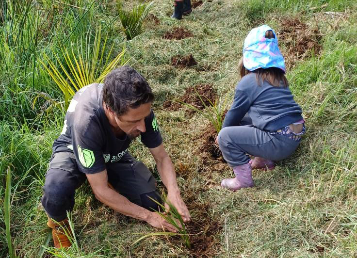 An adult planting with one child.