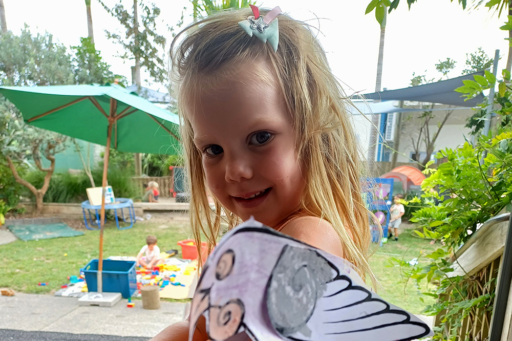 Girl has out-stretched hand with paper puppet.