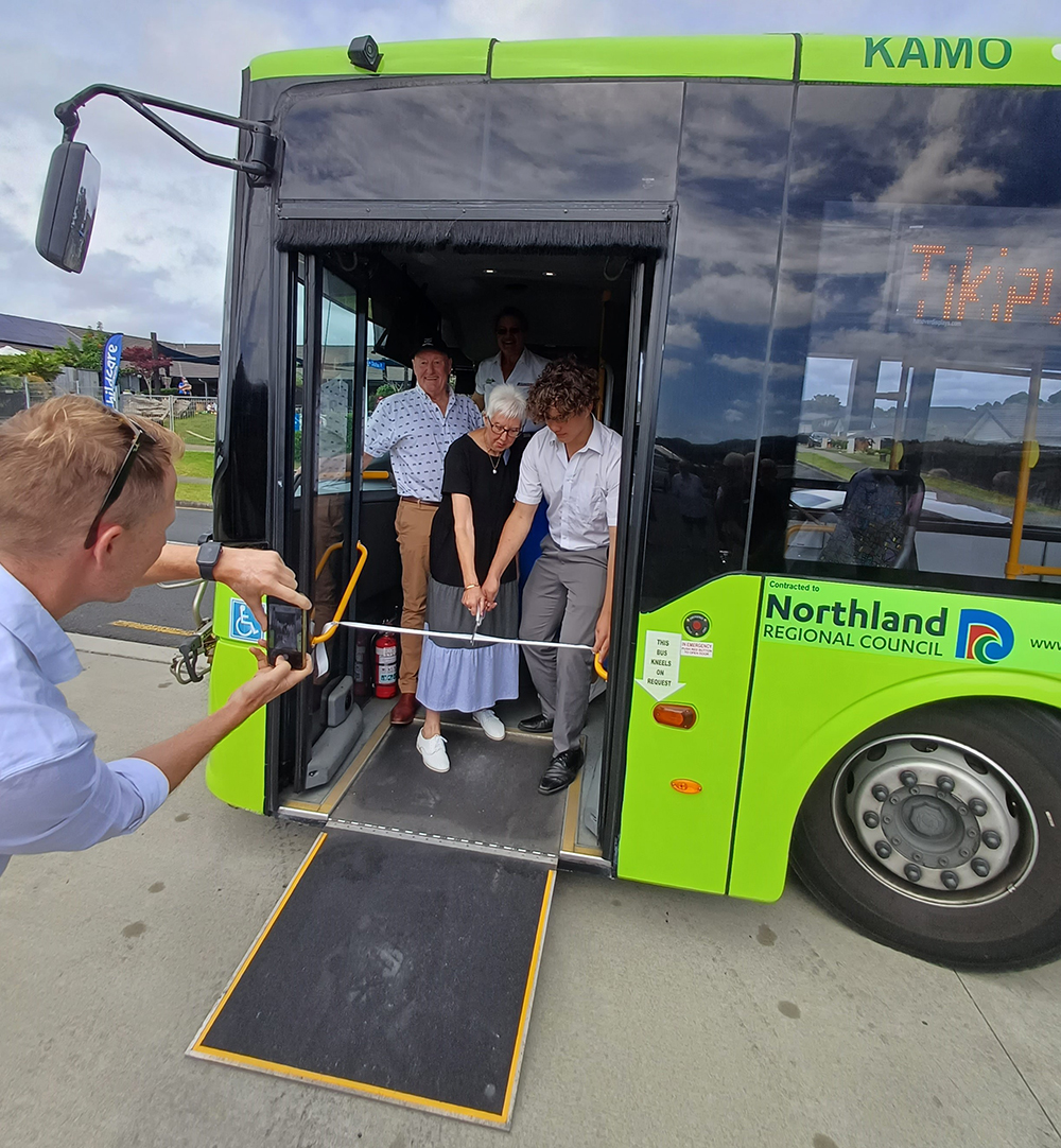 People on a bus cutting a ribbon.