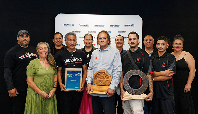 Group of men and women holding trophies and a certificate in front of Northland Regional Council logo backdrop. (Photo: Dawn Dutton Photography).