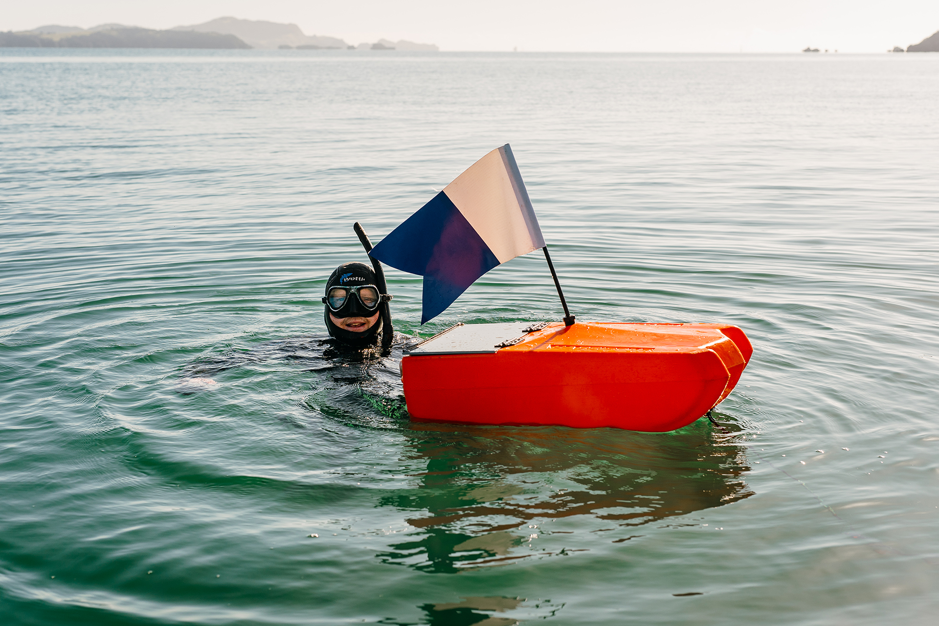 Diver in water with dive flag and float.