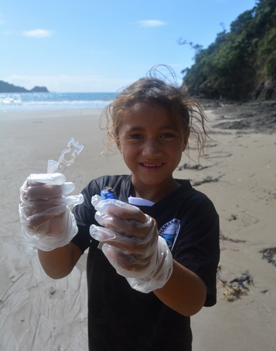 Whananaki School student holding rubbish from the beach.