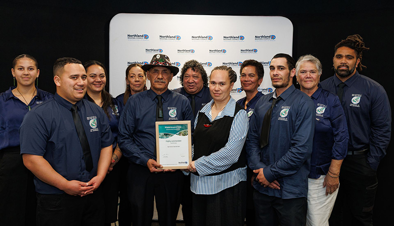 Group of men and women holding trophies and a certificate in front of Northland Regional Council logo backdrop. (Photo: Dawn Dutton Photography).