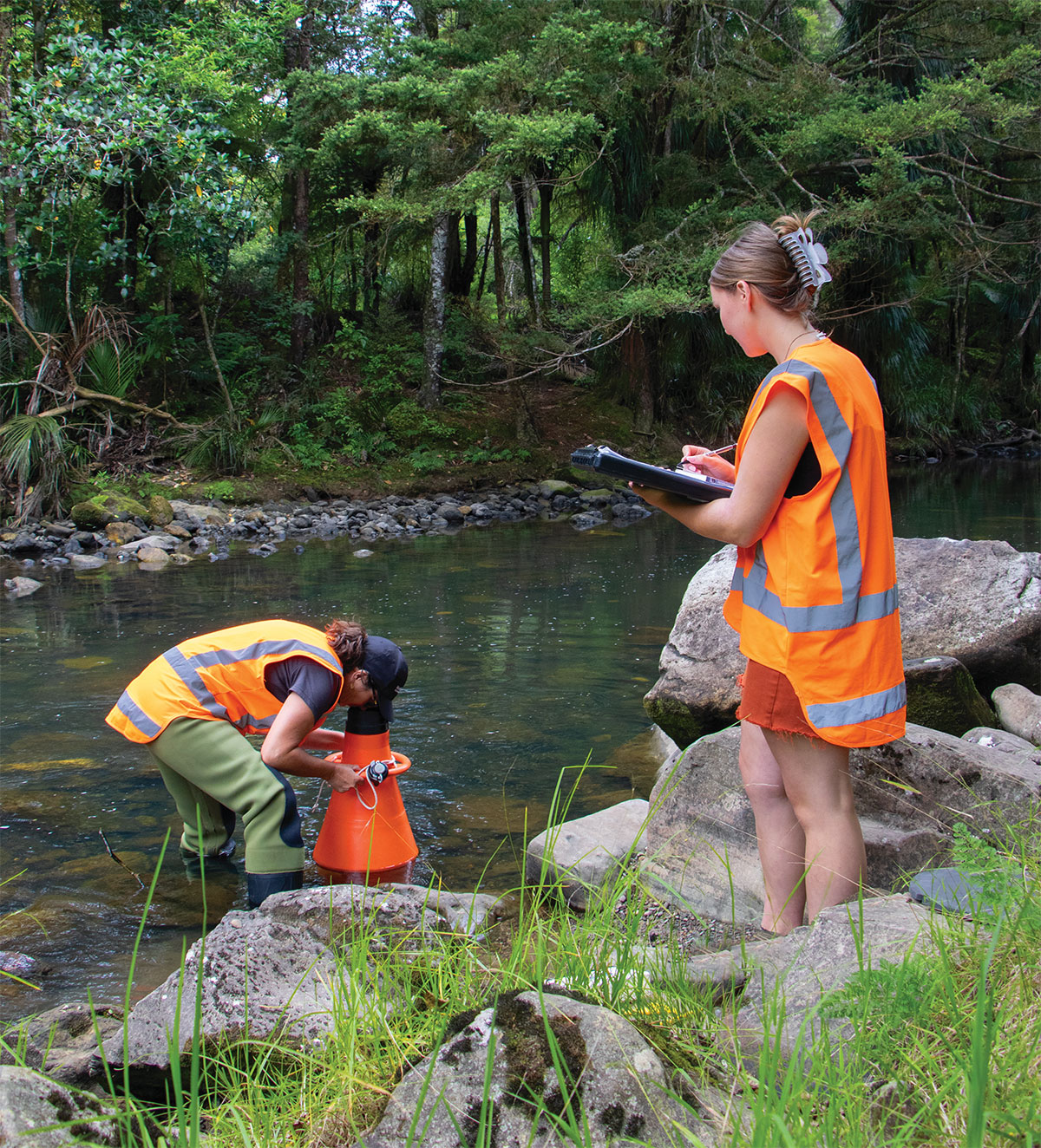 Two women wearing hi-vis doing freshwater monitoring.