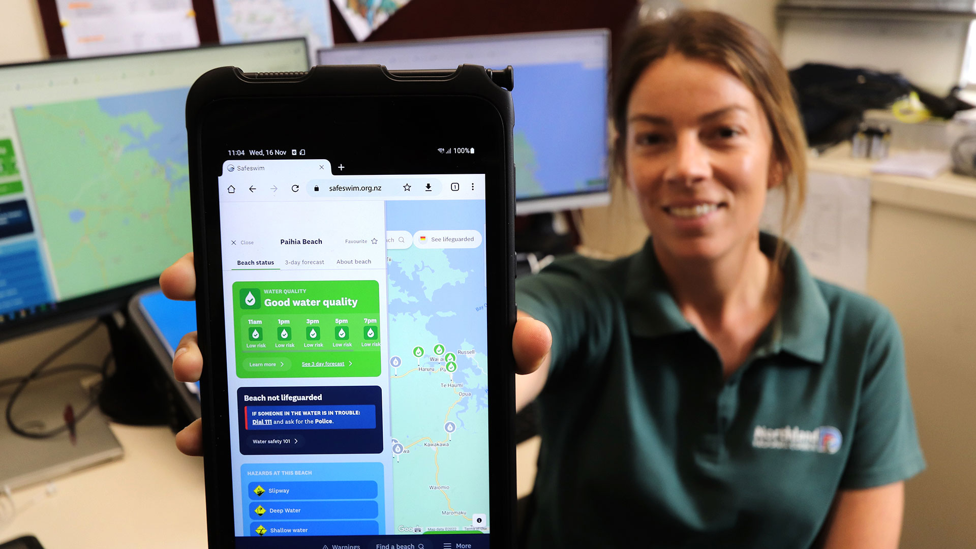 A woman holds a phone displaying the Safeswim app.