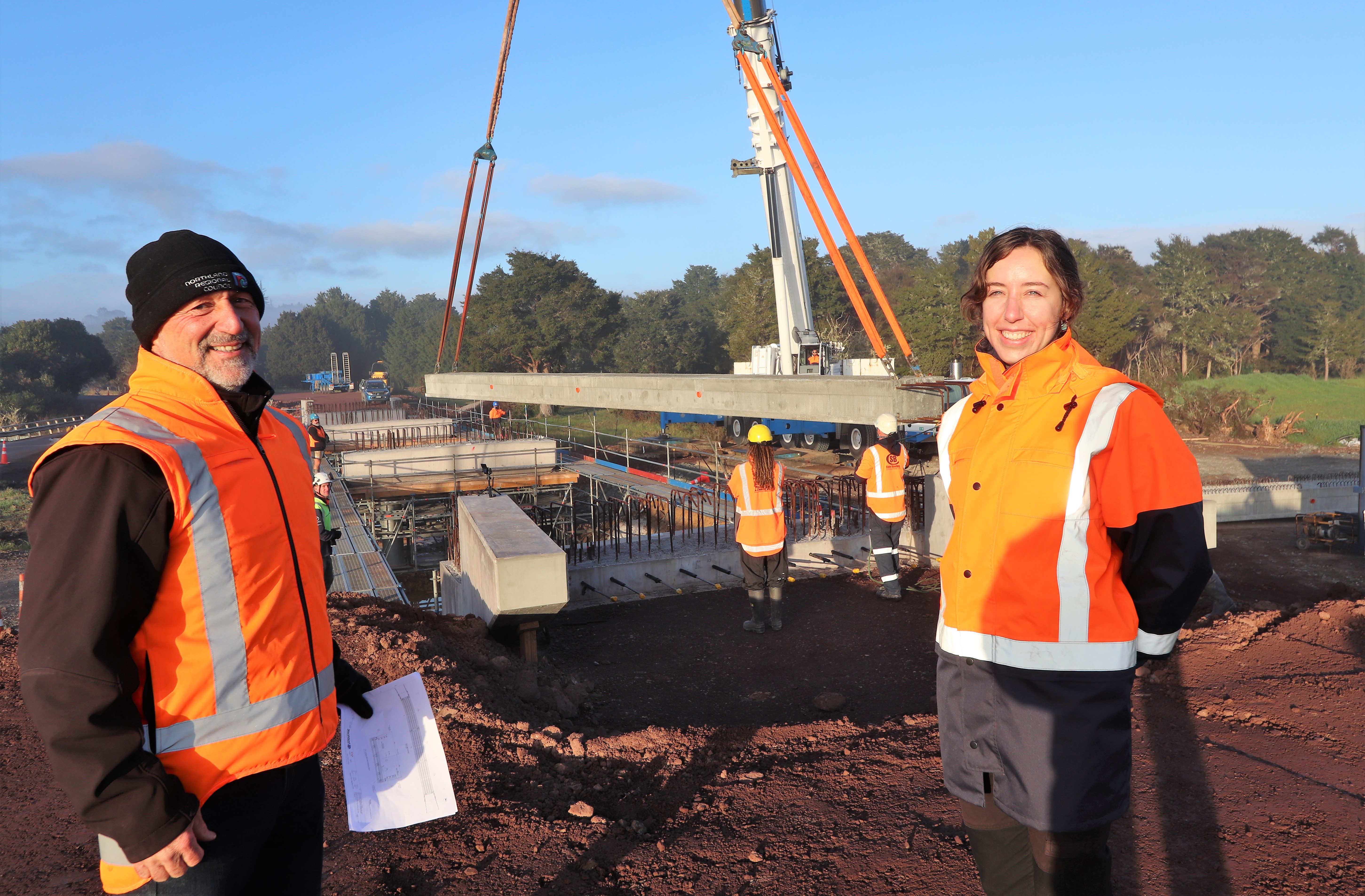 Northland Regional Council Rivers and Natural Hazards Manager Joseph Camuso and Rivers Project Manager Meg Tyler at the site of the new Pokapu Rd bridge as the first of 15 roughly 25 tonne beams is craned into place recently.