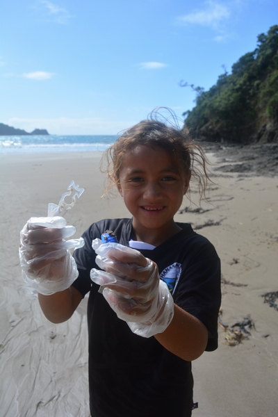Girl holding pieces of rubbish collected from beach.