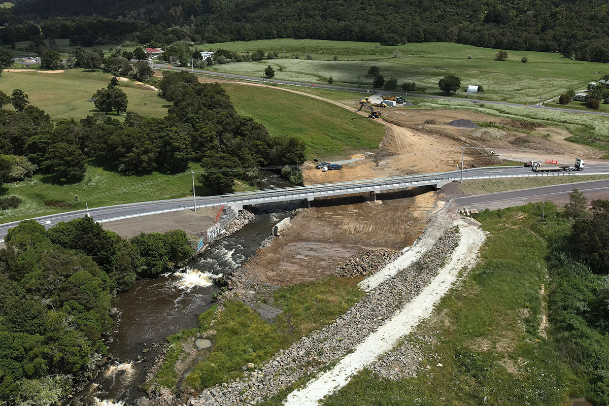 An aerial view of the spillway and bridge over a river in farmland.