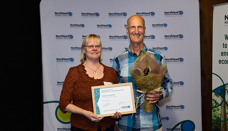 Man and woman with flax flowers and certificate.