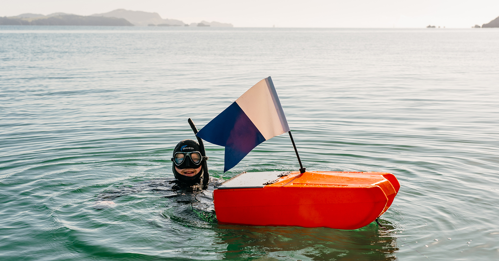 Diver in water with orange float and blue and white dive flag.