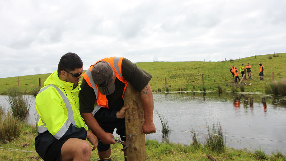 Two men fencing a waterway.