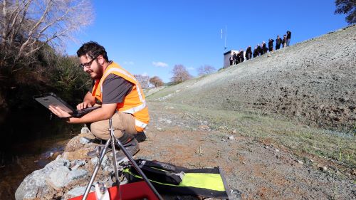 Man with data equipment by the river.