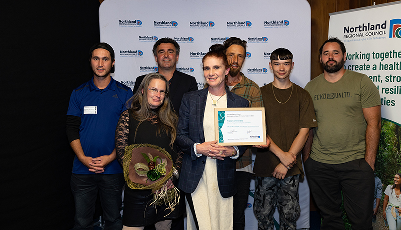 Group of people with flax flowers and certificate.