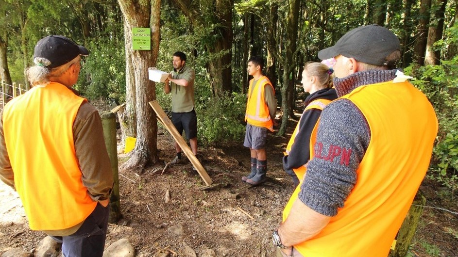 People in hi-vis watching trapping demonstration.