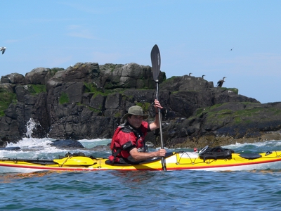 Man paddling kayak near coast.