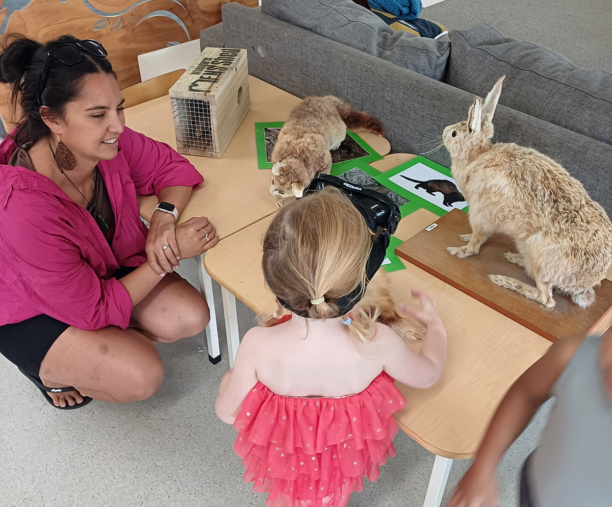 Child and adult stand at table with taxidermy animals.