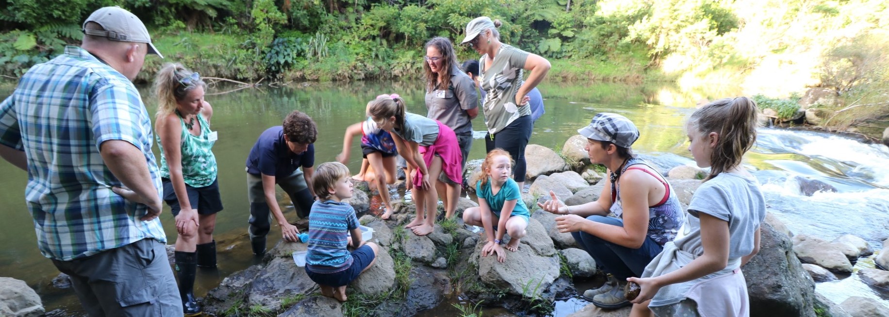 Students and teachers on river rocks.