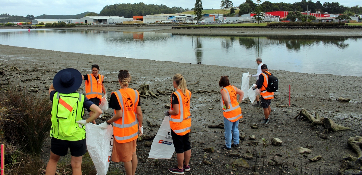 People collecting litter along a river bank.