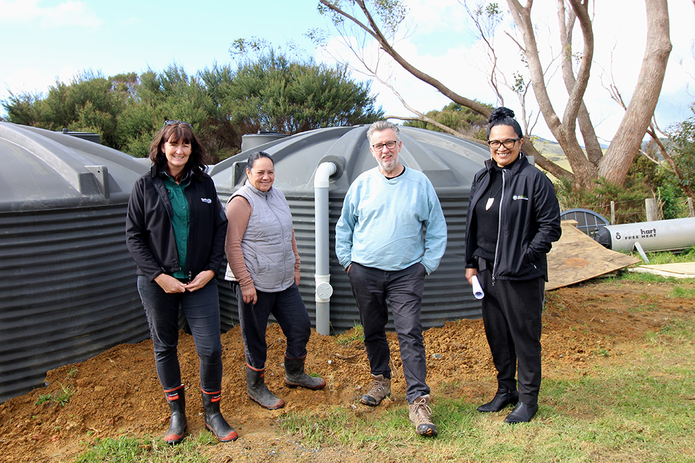 Four people in front of water tanks.