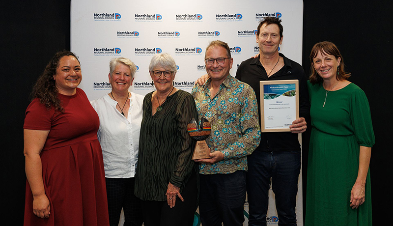 Four women and two men with trophy and certificate in front of Northland Regional Council logo backdrop. (Photo: Dawn Dutton Photography).