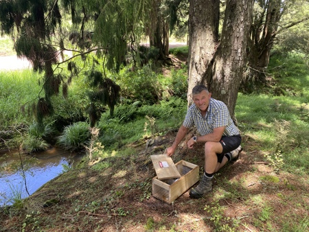 Geoff Crawford next to a stream with a trap.