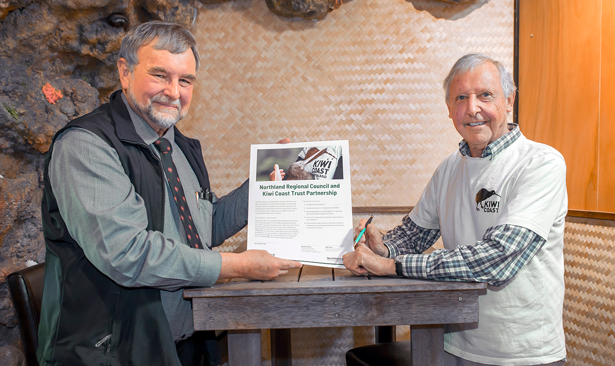 Two men at a table with signed agreement.